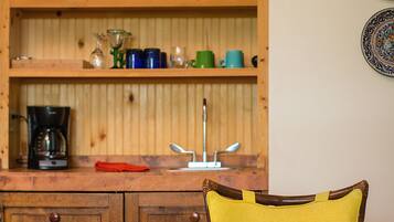 A kitchen with wooden cabinets, a coffee maker, and a sink.