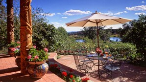 An outdoor patio with a table and chairs, surrounded by potted plants and a view of a lake. - Blue Lake Ranch (Hesperus)