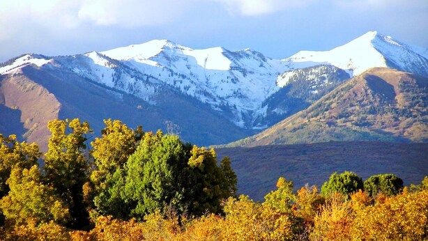 A mountain landscape with snow-capped peaks and autumn foliage in the foreground. - Blue Lake Ranch (Hesperus)