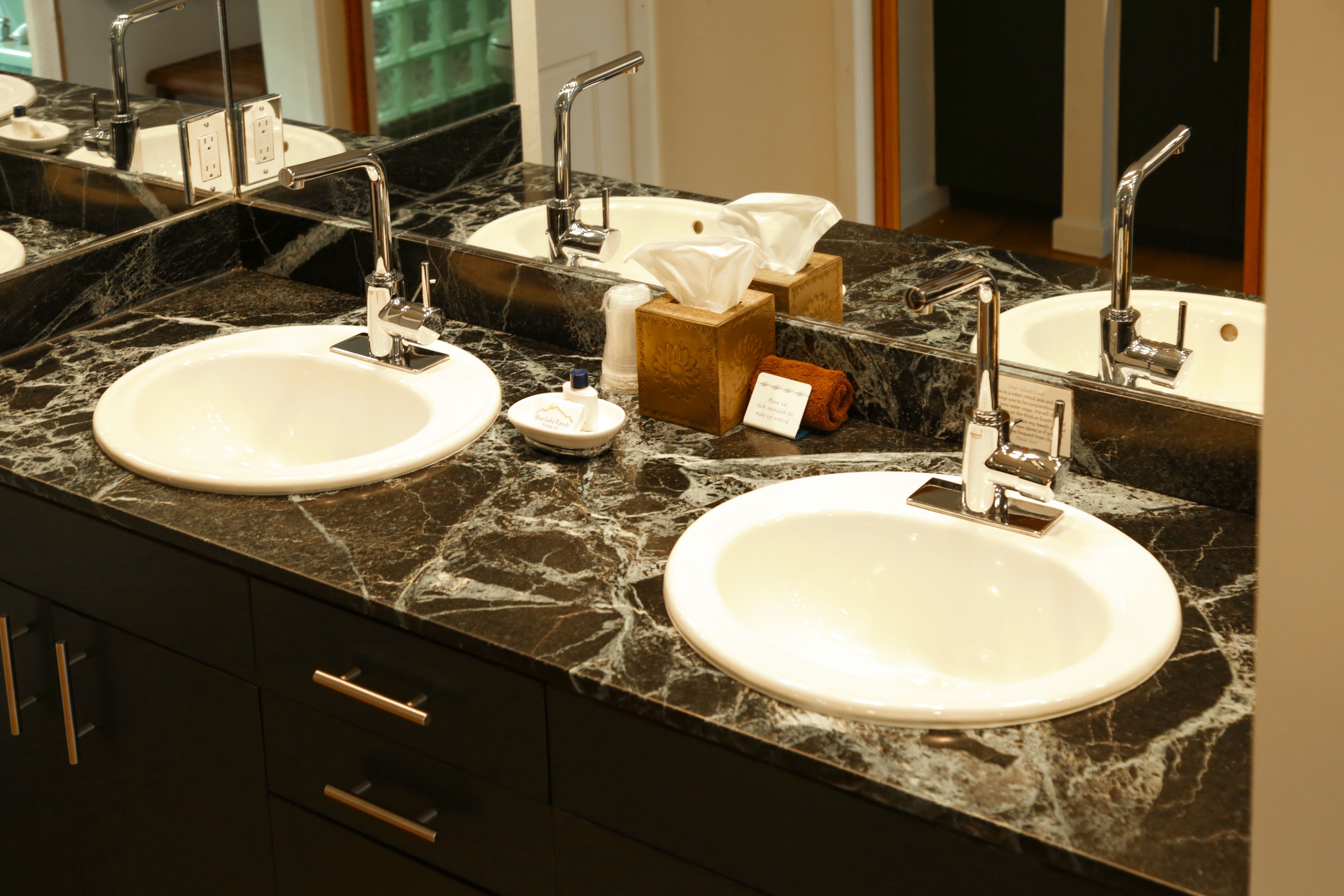 A bathroom with two sinks, marble countertops, and a mirror.