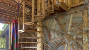 A wooden cabin interior with a spiral staircase, a round table, and a rustic fireplace. - Blue Lake Ranch (Hesperus)