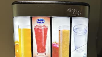 Una máquina de café con cuatro opciones de bebidas: zumo de naranja, zumo de arándano, zumo de manzana y agua.