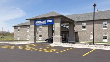 Welcome to Midland Inn & Suites, featuring a stone facade and covered entrance.