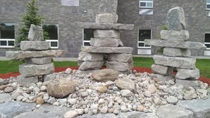 A stone structure in a landscaped area with a building in the background. - Midland Inn & Suites (Midland)