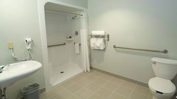 Un baño con lavamanos, inodoro, ducha y barras de apoyo.