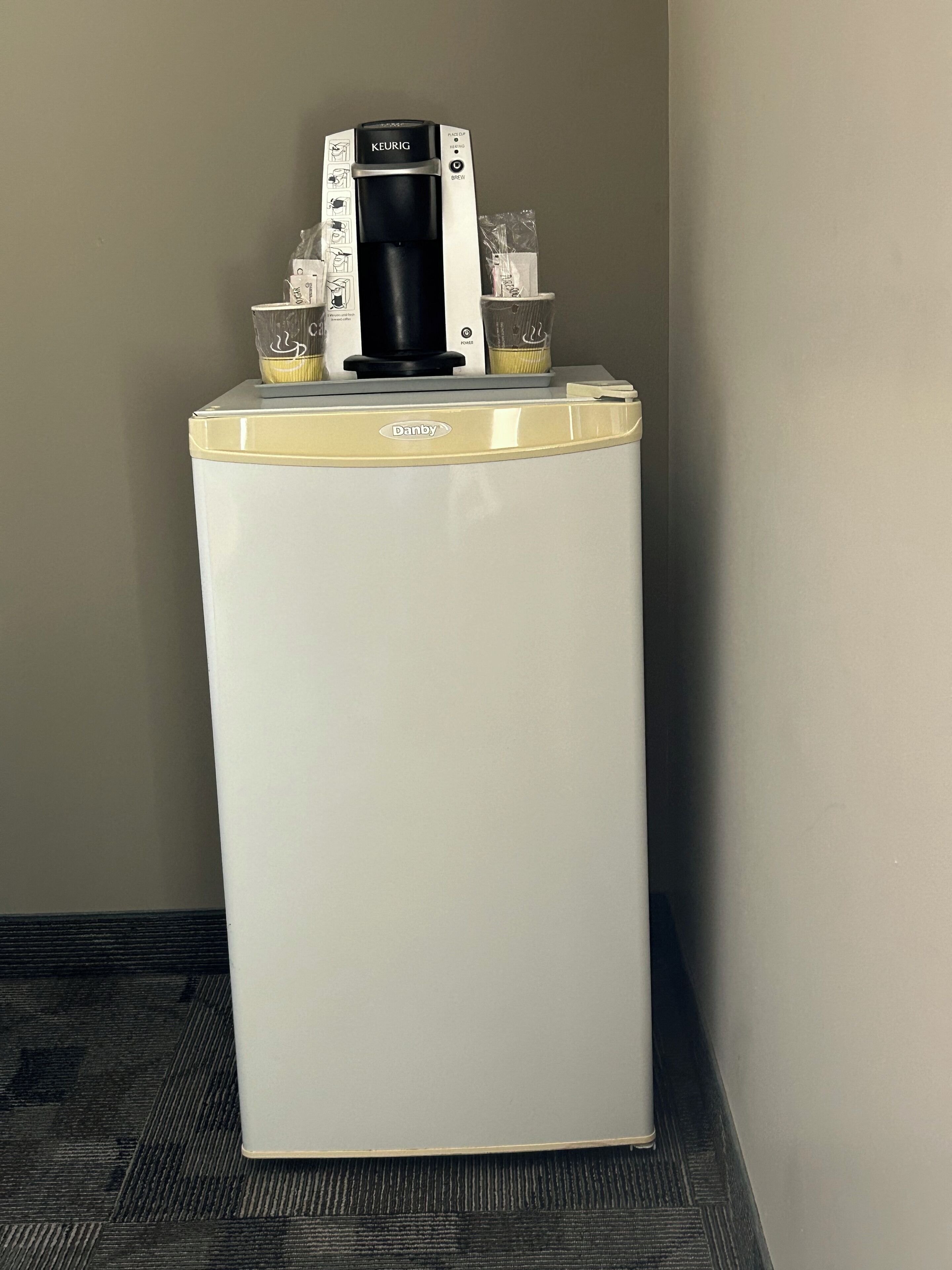 Un refrigerador Danby blanco y dorado con una cafetera KEURIG encima.