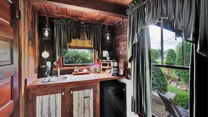 A rustic kitchen with wooden cabinets, a sink, and a coffee maker.