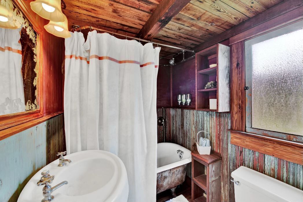 Un baño rústico con una bañera antigua, un lavamanos y un inodoro.