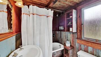 Un baño rústico con una bañera antigua, un lavamanos y un inodoro.