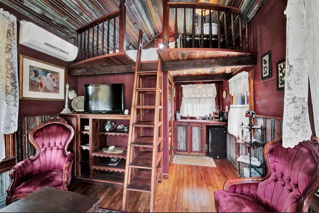 Ein gemütliches Zimmer mit einer Holztreppe, einem Fernseher und zwei komfortablen Sesseln.
