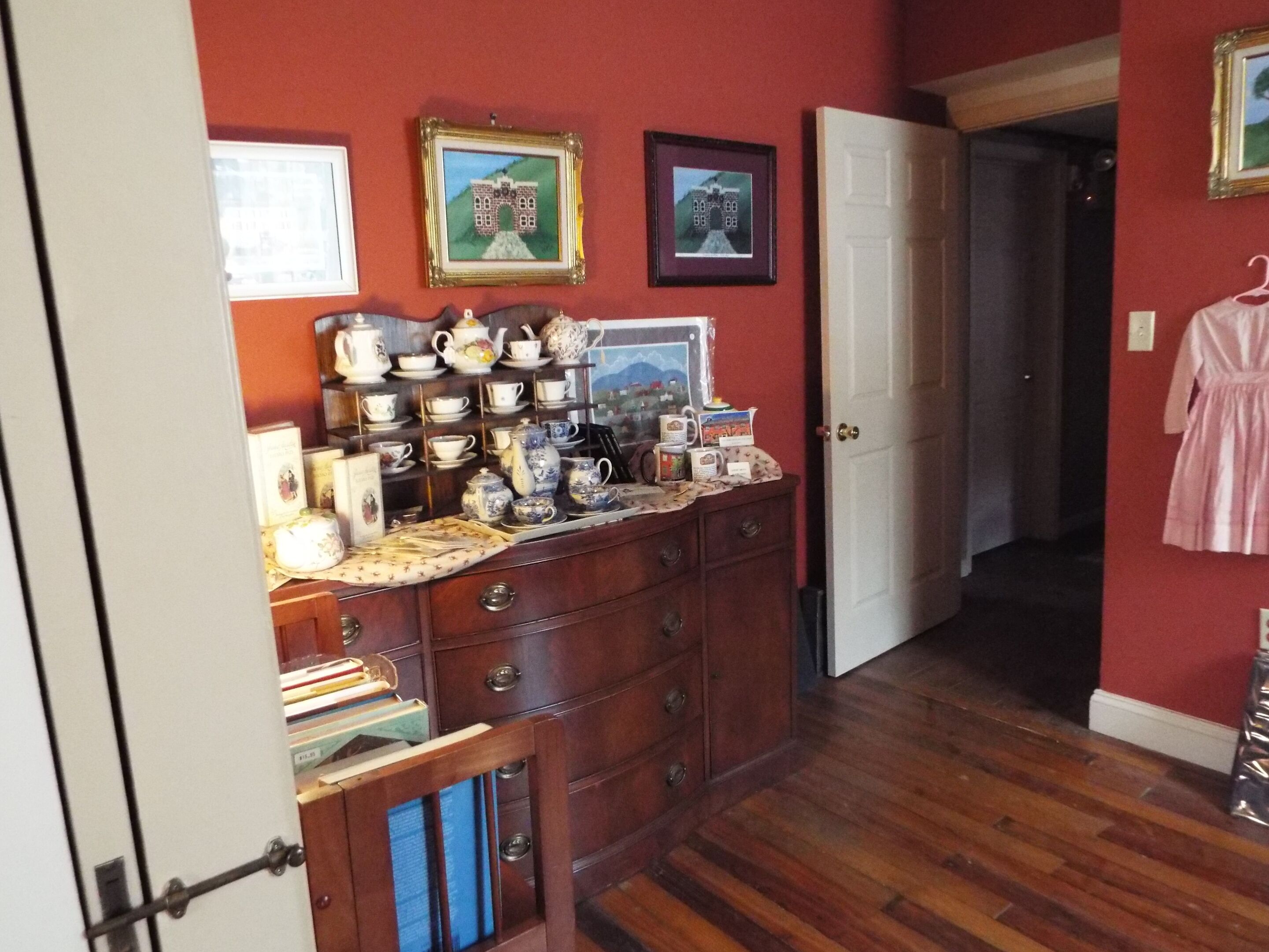 A room with a wooden dresser, a door, and a hallway.