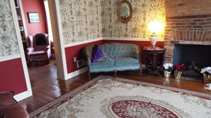 Un salon avec un canapé bleu, un tapis à motifs, une cheminée et un mur rouge.
