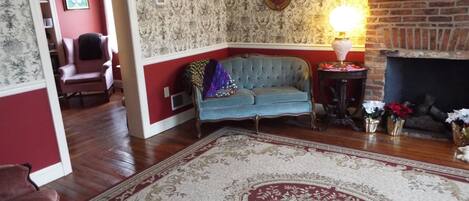 A living room with a blue sofa, a patterned rug, a fireplace, and a red wall.