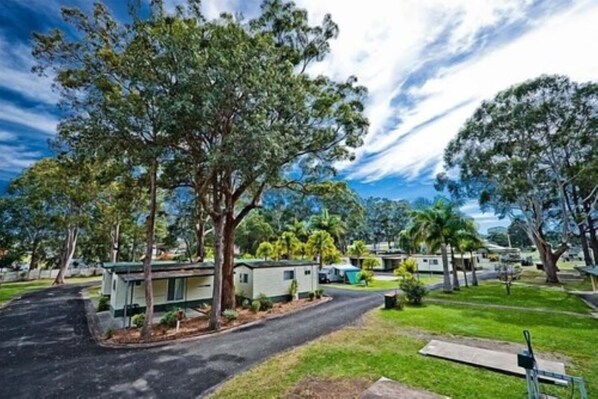 A campground with multiple mobile homes, a paved road, and surrounding trees.