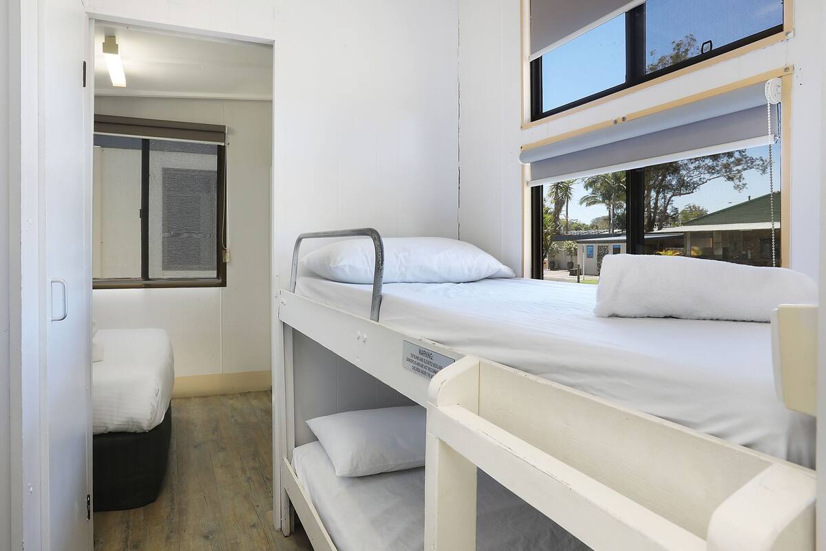 Une chambre d’hôtel compacte avec des lits superposés, une petite fenêtre et une vue sur l’extérieur.
