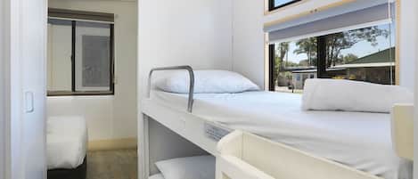 A compact hotel room with bunk beds, a small window, and a view of the outside.