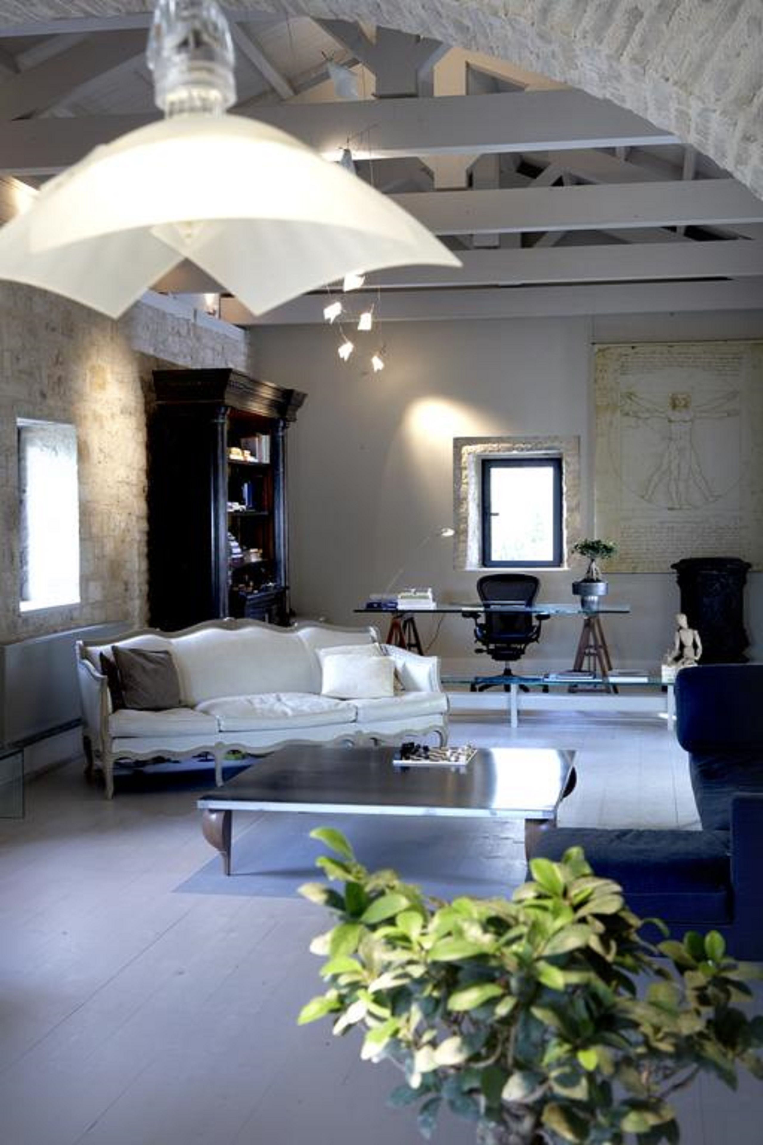A modern living room with a white sofa, a glass coffee table, and a blue armchair. There is a bookshelf and a map on the wall.