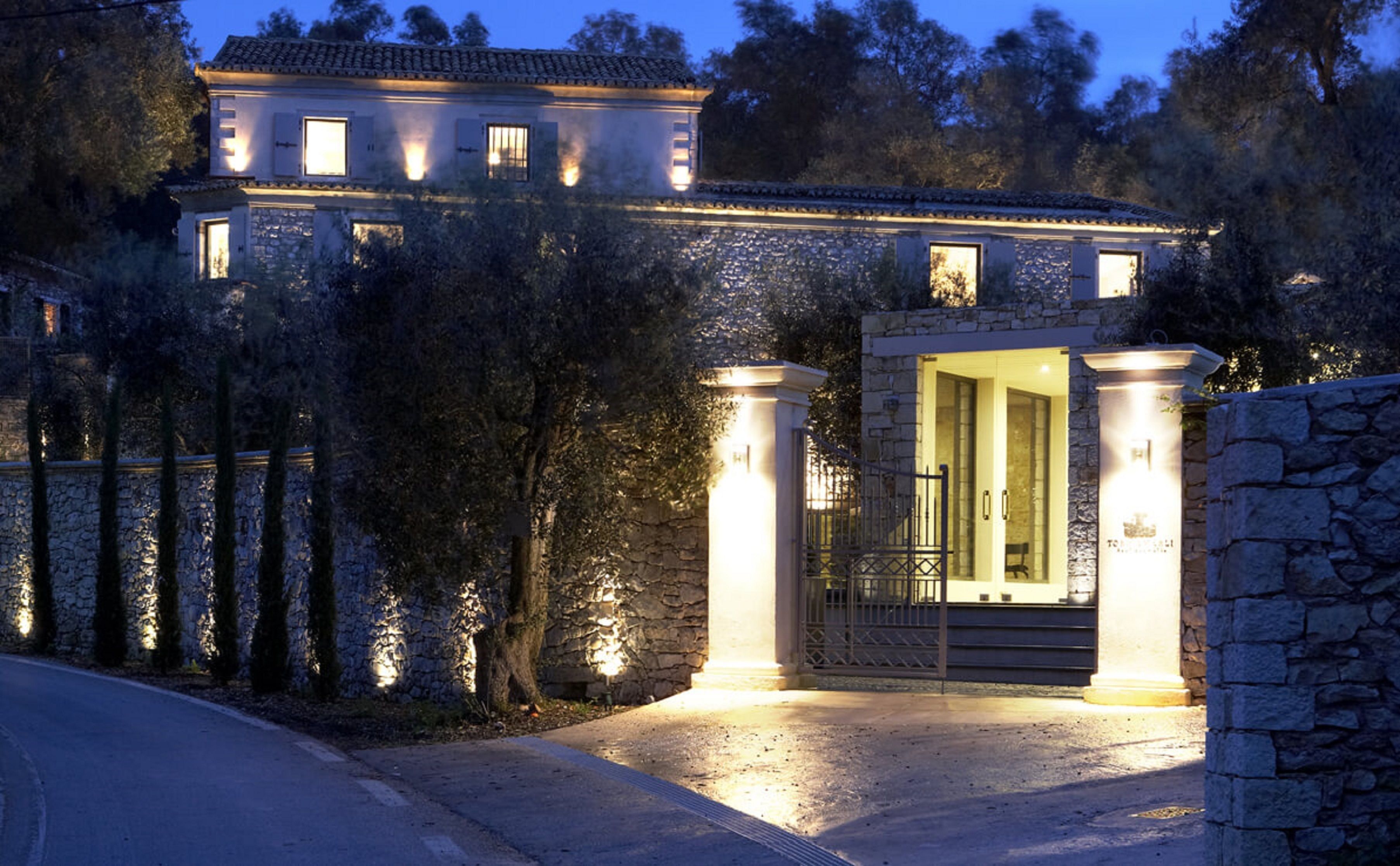 A stone-walled building with a gated entrance, illuminated by exterior lighting.