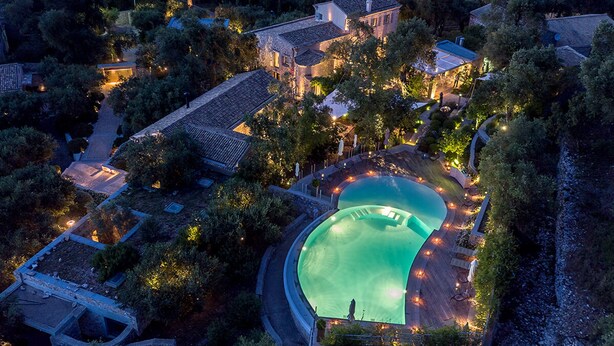 An aerial view of a residential area with a swimming pool, surrounded by trees and houses. - Torri E Merli Hotel by GHH (Paxos)