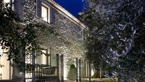 A stone pathway leading to a house with a covered outdoor seating area and a stone wall. - Torri E Merli Hotel by GHH (Paxos)
