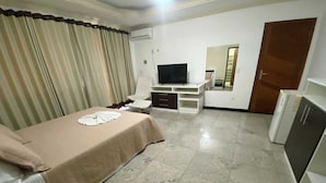 A hotel room with a bed, a TV, a desk, a chair, a wardrobe, and a door. - Pousada Dom Fernandes (Cabo Frio)