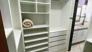 A walk-in closet with multiple shelves and drawers, a tiled floor, and a view of the bathroom through an open door. - Pousada Dom Fernandes (Cabo Frio)
