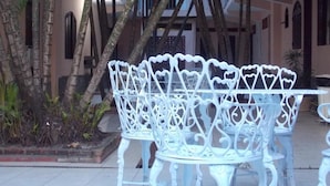 A white metal table and chairs set outdoors with a building in the background. - Pousada Dom Fernandes (Cabo Frio)