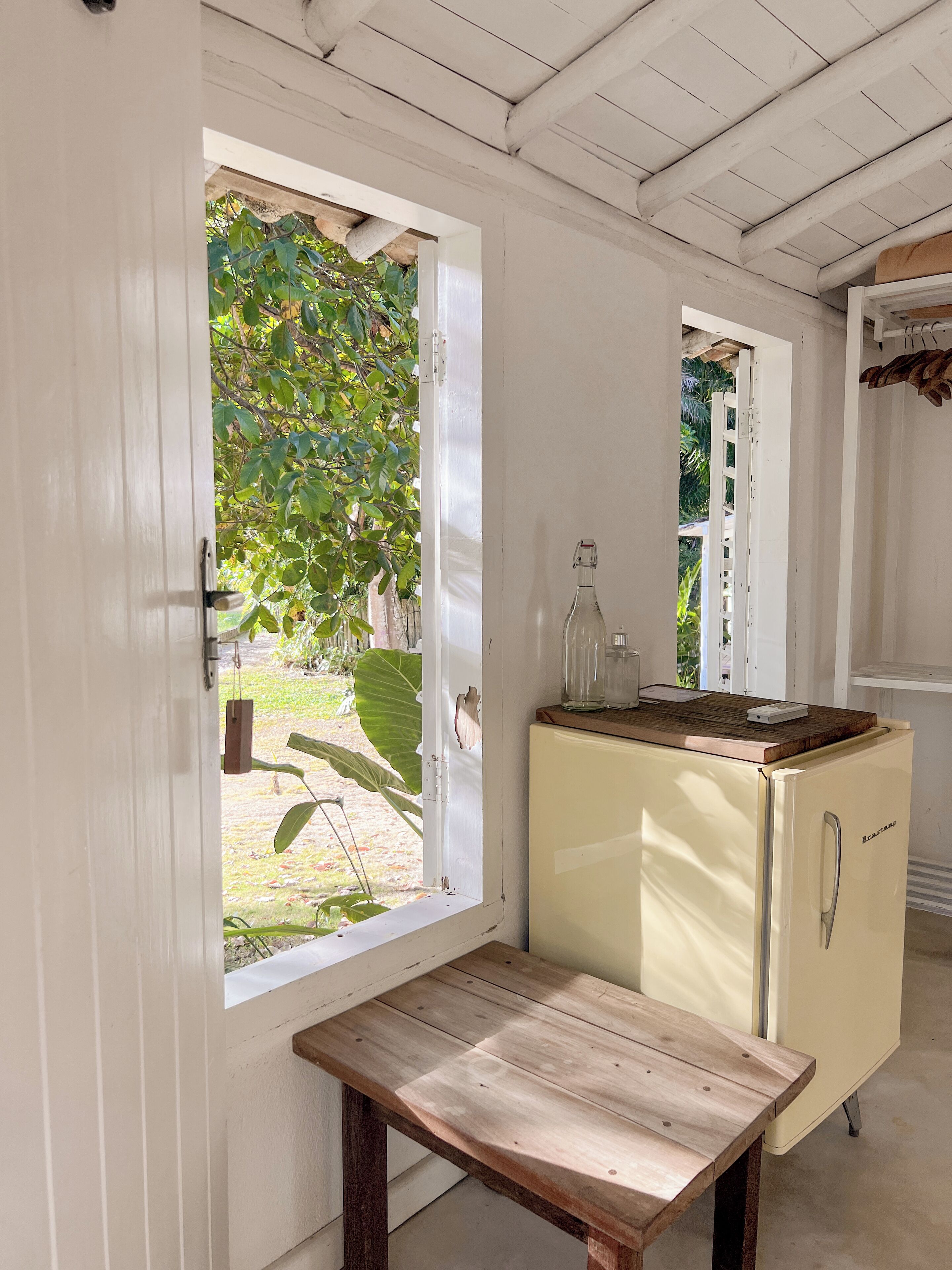 A compact kitchen with a wooden table, a vintage refrigerator, and a window with a view of greenery.