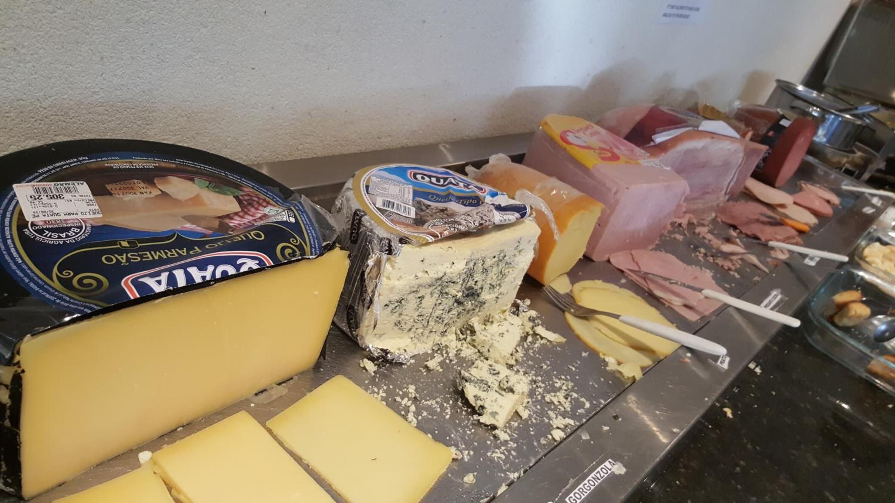 Exhibición de quesos y embutidos con diferentes tipos de queso y fiambre en rodajas.