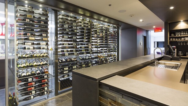 A wine cellar with multiple wine racks and a bar area with a sink. - Chez Truchon (La Malbaie)