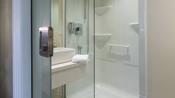 A modern bathroom with a glass-enclosed shower, a white sink, and a mirror.