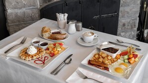 A breakfast table with waffles, toast, fruit, eggs, and coffee. - Chez Truchon (La Malbaie)