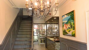 A grand staircase with a chandelier, a wine cooler, and a painting on the wall. - Chez Truchon (La Malbaie)