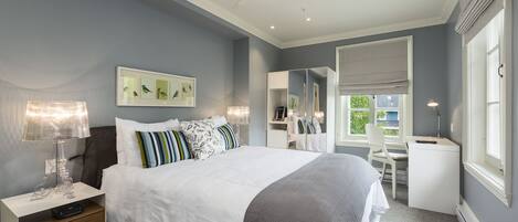 A bedroom with a bed, bedside tables, a desk, and a chair.