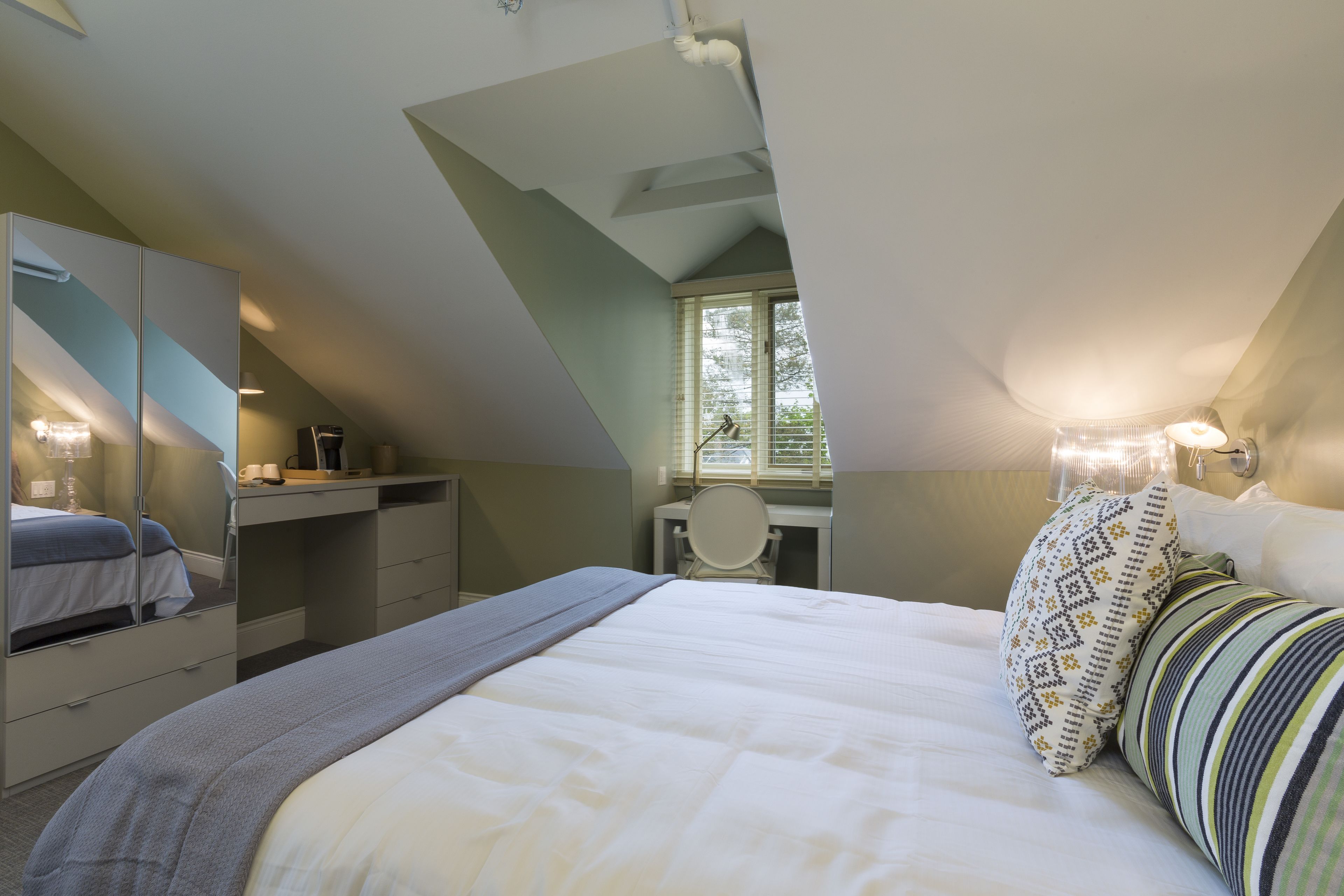Ein Schlafzimmer mit Bett, Schreibtisch, Stuhl und Fenster.