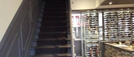 Eine Treppe führt zu einer niedrigeren Ebene, auf der rechten Seite befindet sich ein Weinkühlschrank.