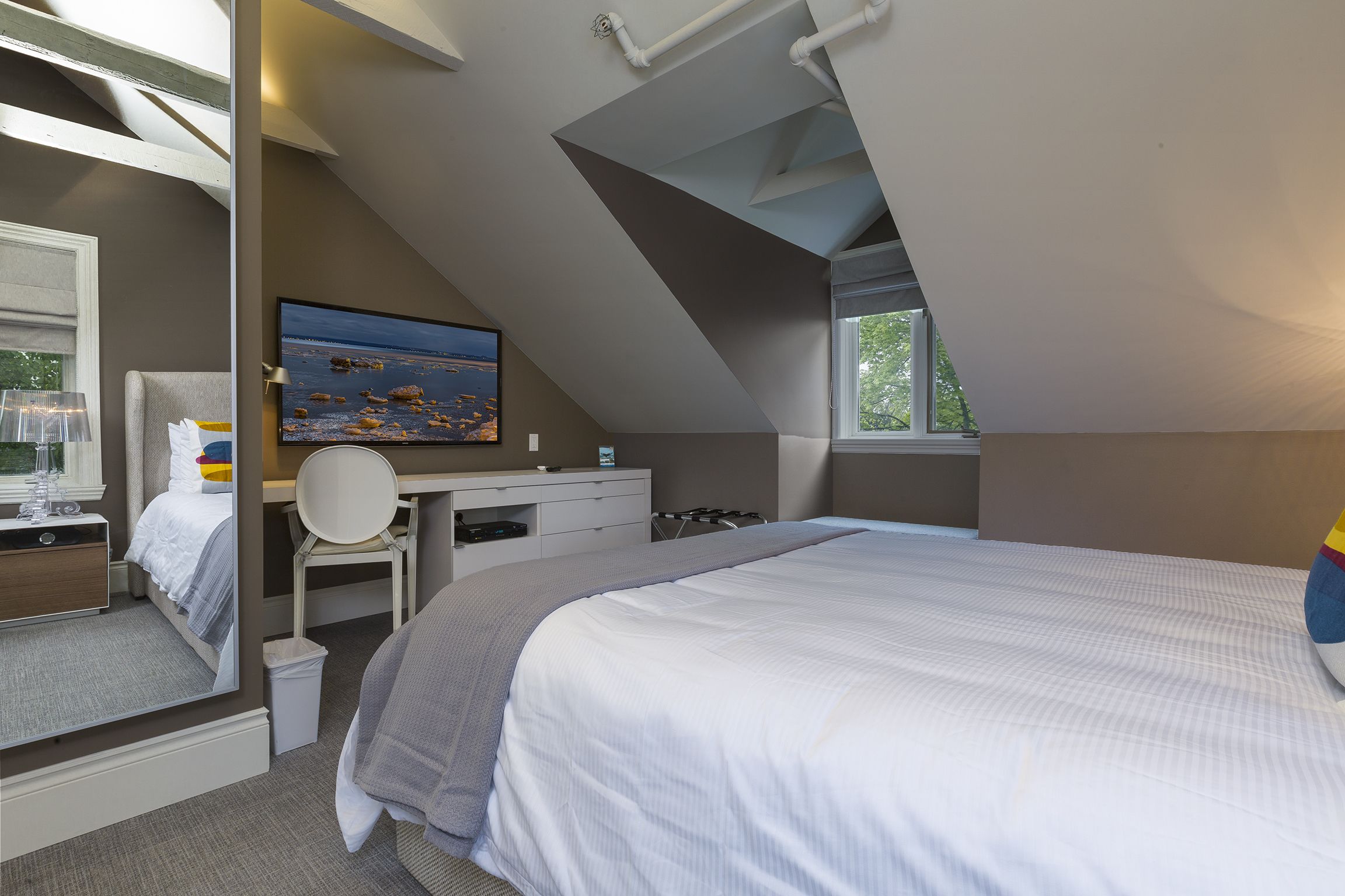 Une chambre à coucher avec un lit, un bureau, une chaise, une télévision et une fenêtre.
