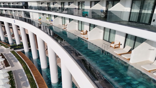 Un hôtel moderne doté d’une piscine centrale, de nombreux balcons et d’espaces de détente en plein air.