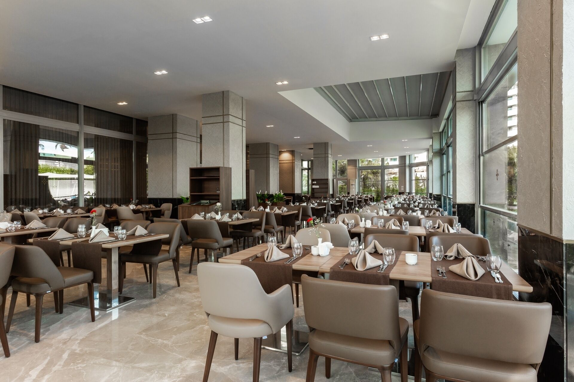 Un restaurante espacioso con varias mesas y sillas, amplias ventanas y una decoración de diseño moderno.