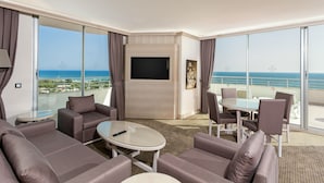 Une chambre d’hôtel moderne dotée d’un balcon, d’une télévision à écran plat et d’un coin repas avec une table et des chaises.