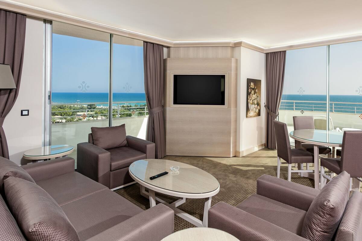 Une chambre d’hôtel moderne dotée d’un balcon, d’une télévision à écran plat et d’un coin repas avec une table et des chaises.