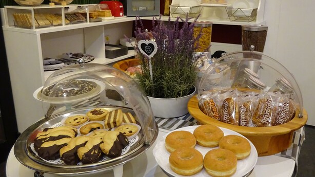 A buffet with various baked goods, including cookies and pastries, and a plant with a decorative heart-shaped sign. - 7MOTEL - SETTIMOTEL (Settimo Milanese)
