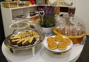 A buffet with various baked goods, including cookies and pastries, and a plant with a decorative heart-shaped sign. - 7MOTEL - SETTIMOTEL (Settimo Milanese)