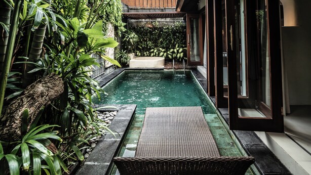 Una piscina privata con un pontile in legno, immersa nel verde e circondata da una recinzione in legno.