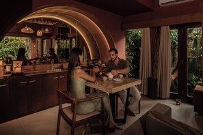 Une cuisine moderne avec un plafond incurvé, une table à manger et une grande fenêtre avec des rideaux.