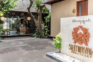 Une enseigne pour le Seminyah Sanctuary, avec un logo, entourée d’un jardin agrémenté d’arbres et de plantes.