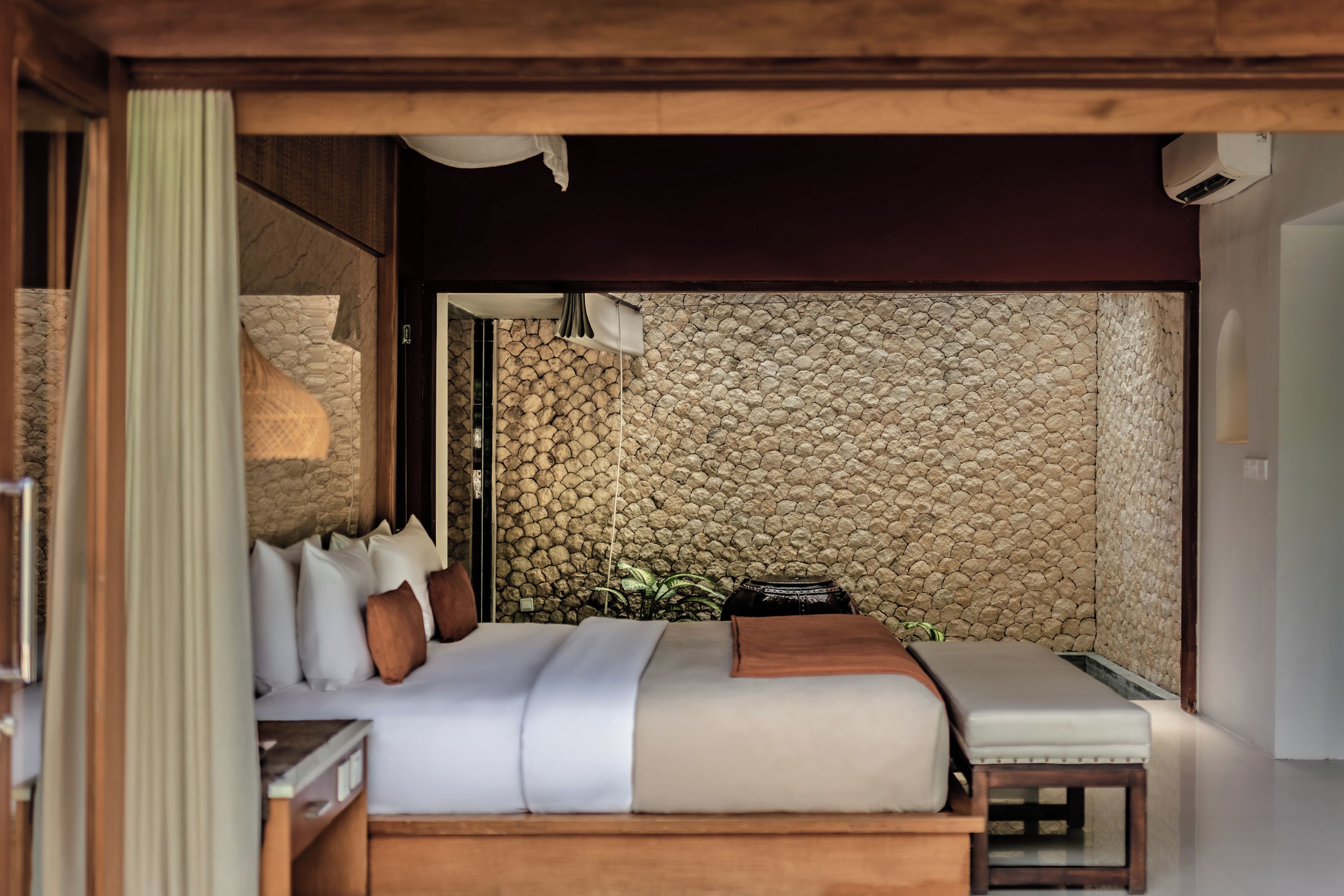 Un dormitorio con cama, mesita de noche y pared de piedra.