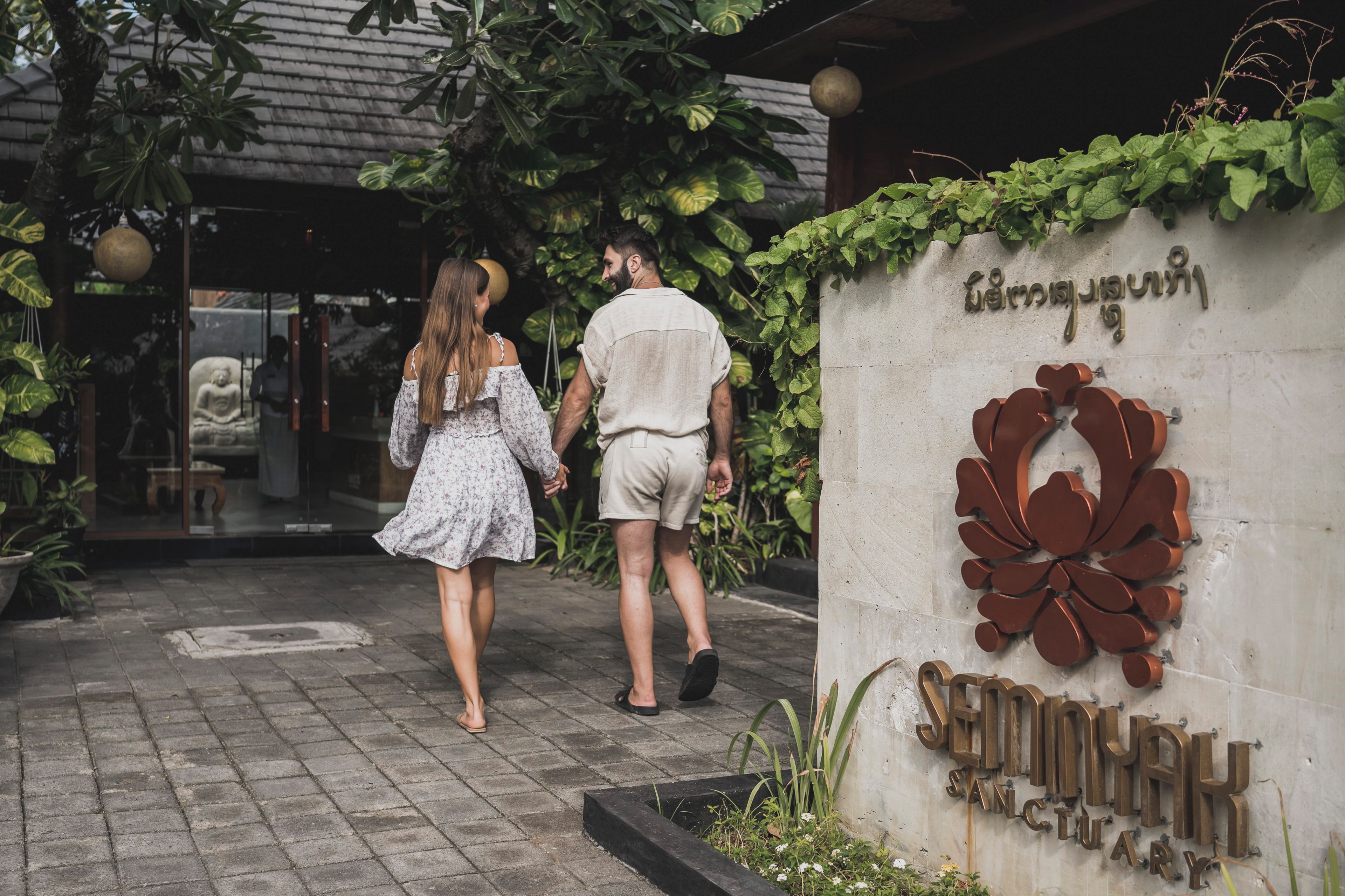 A couple walking towards a building entrance with a sign that reads 'Sembawa Sanctuary'.