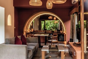 A modern living room with a sofa, a coffee table, and a dining area with chairs and a table. - Seminyak Sanctuary Villa by Ini Vie Hospitality (Legian)