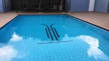 A rectangular swimming pool with a tiled edge and a ladder on one side.